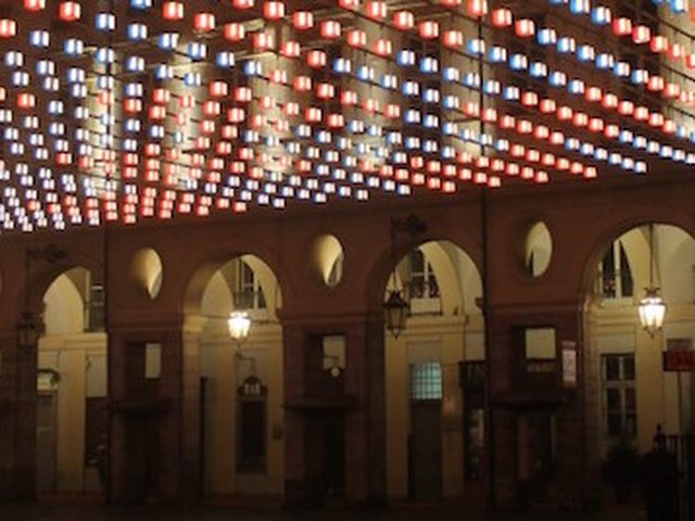 Portici di Torino illuminati di notte da una distesa di luci rosse e blu