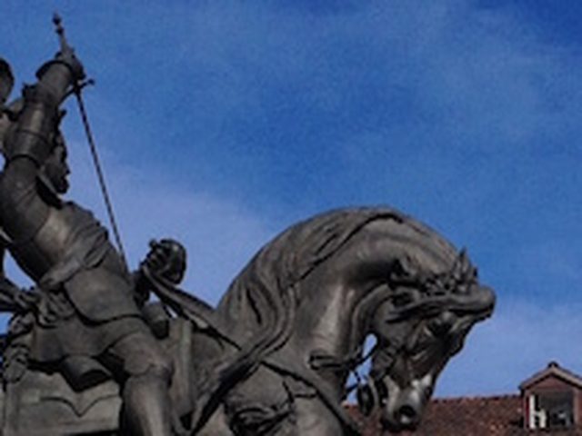 Monumento equestre in bronzo contro il cielo blu e i tetti di Torino